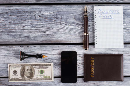 Money, notebook with business plan. Office guy stuff. Personal objects in dark colours.の写真素材