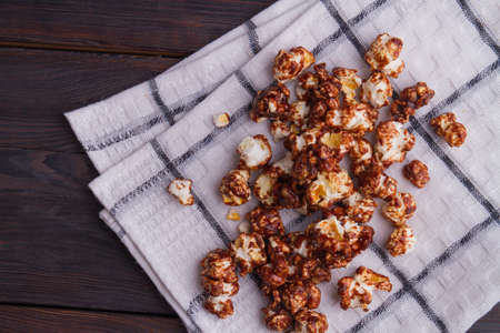 Scattered chocolate popcorn grains on white napkin. Dark brown background.の写真素材