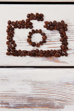 Coffee beans art. Brown grains on white wooden planks.