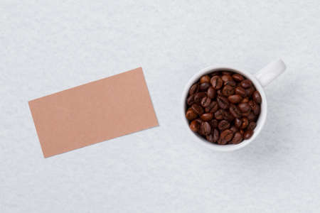 Top view cup filled with coffee beans and blank paper. Isolated on white.の写真素材