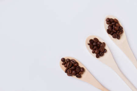 Wooden spoons with roasted coffee beans. Isolated on white background. Top view flat lay.