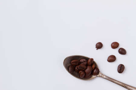 Teaspoon with coffee beans on white background. Close up silver spoon with coffee seeds. Top view flat lay.の写真素材