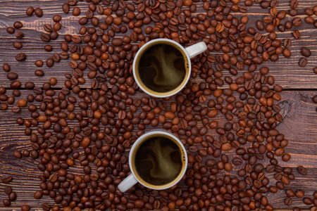 Cups of hot coffee and coffee beans. Top view flat lay. Brown wooden background.の写真素材