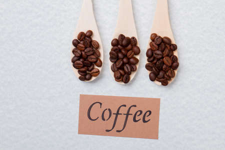 Row of three wooden spoons with coffee beans. White isolated background.の写真素材