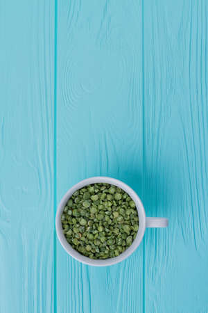 Top view cup of green split peas. Blue wooden background.の写真素材