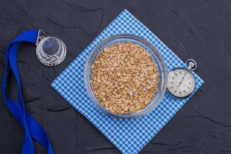 Sport and healthy lifestyle concept flat lay. Plate of oatmeal with silver medal and stopwatch.の写真素材