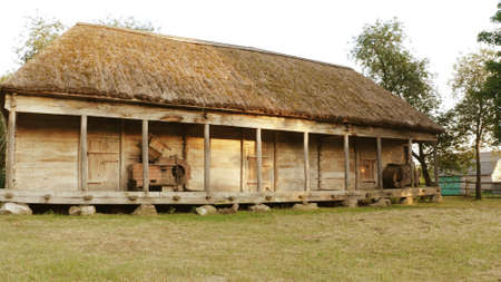 Old log house. Meadow in front of the house. Part of the roof is supported by wooden columns.の写真素材