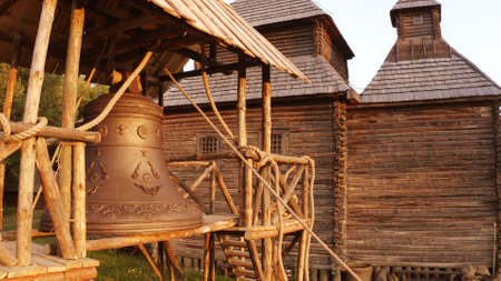 Large old bell in the village. Wooden small church on the background.の写真素材