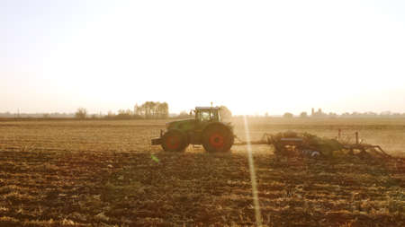 Tractor working on large farm field. Field cultivation after harvest. Agriculture and farming concept.の写真素材