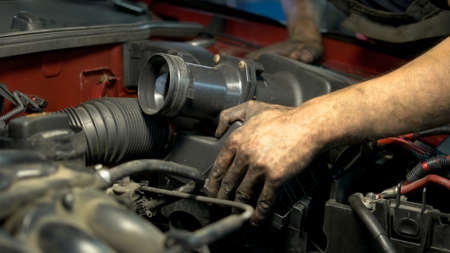 Young professional car service worker installing car engine detail. Repairing fixing car motor.