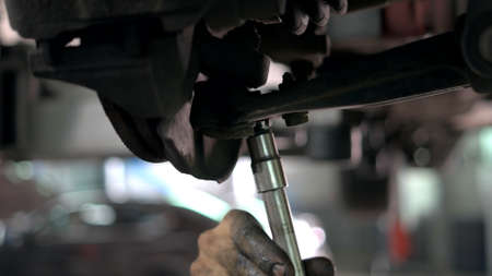 Close up unscrewing car nuts. Auto mechanic with dirty hands uninstalling som car detail.の写真素材
