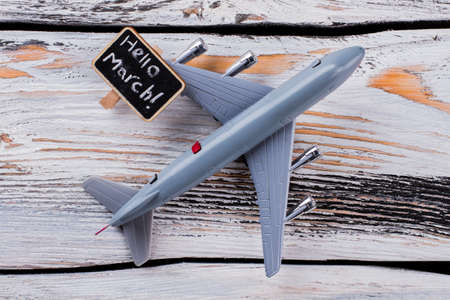 Flat lay toy plane and hello march tagline. Old white wooden table on the background.の写真素材