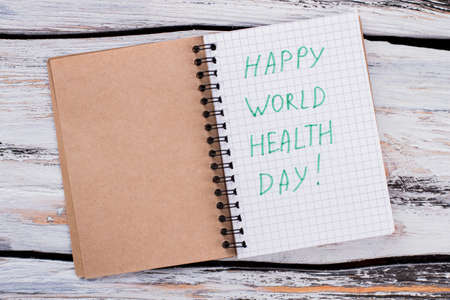 Happy world health day concept. Opened notepad with wishes. White wooden table.の写真素材