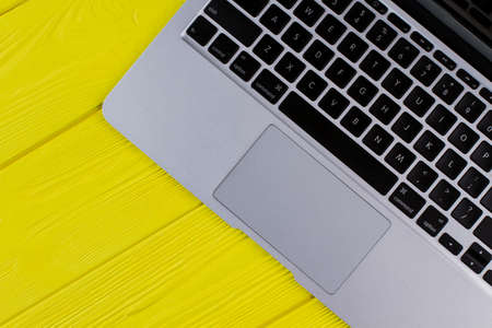 Top view laptop keyboard. Yellow wooden background.