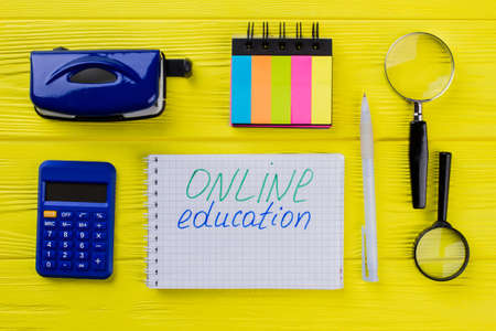 Online education concept flat lay. Office stationery items on yellow wooden table.