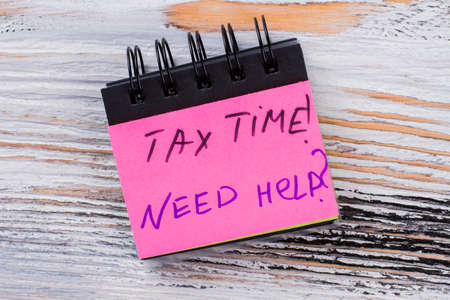 Tax time message on a paper of mini notepad. Need any help with your taxes. White wood on the background.の写真素材