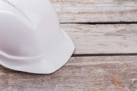 Close up white worker counstructor helmet. Builders plastic cap on wooden table.の写真素材