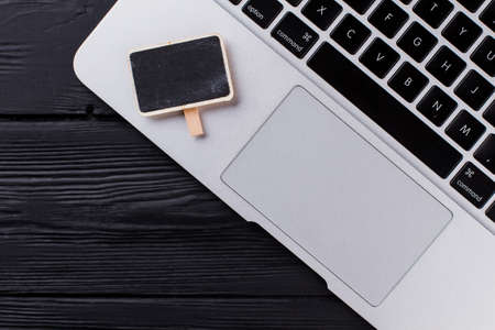 Top view close up laptop keyboard and touchpad. Small board with black screen. Dark wooden table...