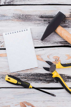 Blank notepad and construction workers instruments. Top view flat lay. White wooden backgroiund.の写真素材
