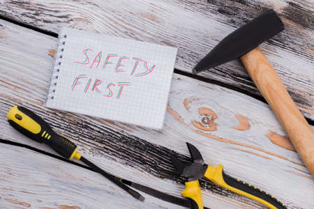 Safety first notice and household repairing tools. Top view flat lay. Old wooden background.の写真素材