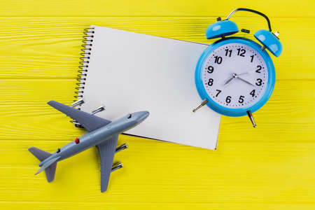 Time travel concept and blank notepad for copy space. Yellow wooden background.