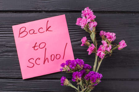 Back to school concept. Bouquets of pink and purple flowers on dark wooden table.の写真素材