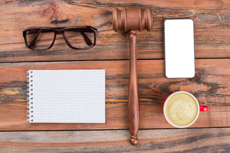 Minimal workspace mobile phone gavel cup of coffee on wood table. Law written on white sticker.の写真素材