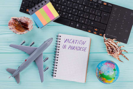 Tourist stuff with notebook, toy airplane, seashell, globe on blue background. Flat lay from above.の写真素材