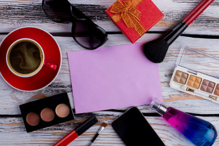 Blank paper and womens makeup accessories. Female things arranged around of pink paper. Topview from above flat lay.の写真素材
