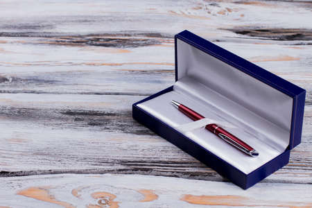 Luxury pen in a blue gift box. White wooden background.
