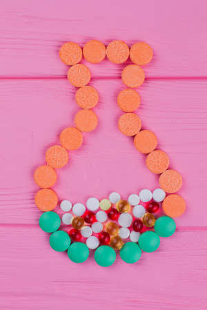 Colored round pills in a shape of a jar on pink wood. Topview flay lay.の写真素材
