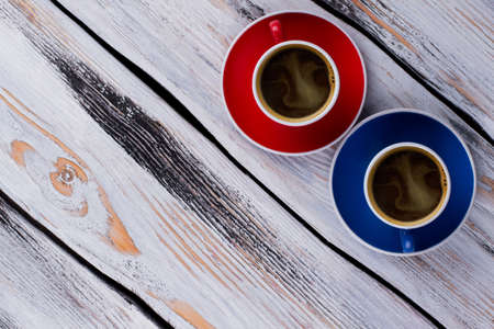 View from above on two cups of delicious coffee. Red and blue coffee cups on vintage white table surface.の写真素材