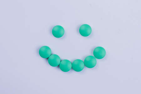 Smiley made of green round pills isolated on white. Antidepressant drugs concept. Topview flat lay.の写真素材