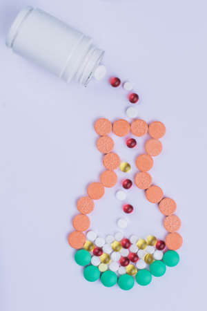 Pills drugs in a shape of a jug isolated on white. White medicine bottle pouring tablets.の写真素材