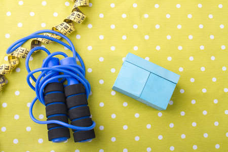 Skipping rope with measuring tape and cupboard on dotted yellow background. Flat lay composition.の写真素材