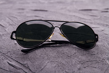 Close up black sunglasses. Dark grunge table background.の写真素材