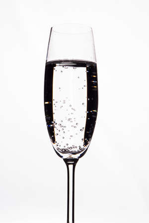 Transparent alcoholic drink with bubbles in a champagne glas cup. Isolated on white background.の写真素材