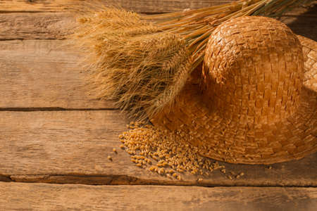 Wheat ears, grain and straw hat. Wheat spikelets, cereal grain and straw hat on vintage wooden...