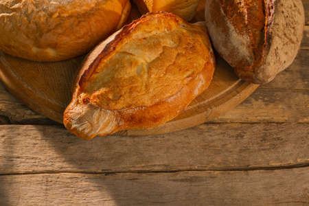 Freshly baked homemade bread on wooden background. Loaves of whole wheat bread on cutting board....