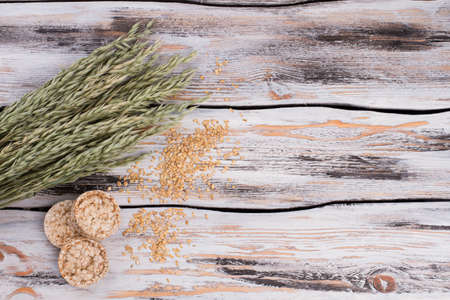 Oat seeds, ears and puffed crispbread. Round crispbread and oat spikelets on vintage wooden...
