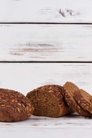 Wholemeal bread on wooden background. Loaf of rye bread cutting into slices. Space for text.