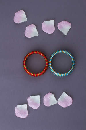 Two braceletes and flowers petals. Isolated on grey background. Flat lay top view.