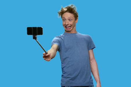 Caucasian teenage boy grimacing while making selfie. Funny teen guy making silly face while posing...