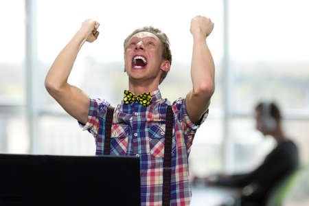 Shocked expressive teen guy celebrating victory. Excited teen boy with computer laptop celebrating...