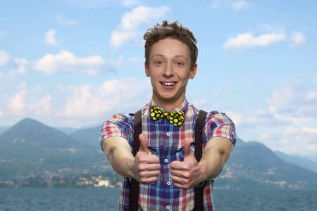 Successful teen boy giving thumbs up to camera. Happy teenage guy showing thumbs up with both hands....