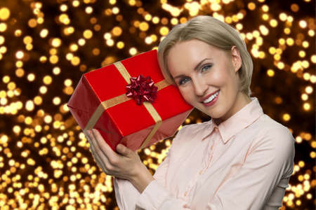 Portrait of young happy woman holding wrapped gift box. Close up satisfied woman received present...
