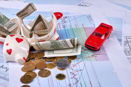 Money savings for a new car concept. Broken piggy bank with currency and coins.の写真素材
