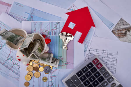 Concept of money savings for a new house. Broken piggy bank with calculator house and keys flat lay.の写真素材