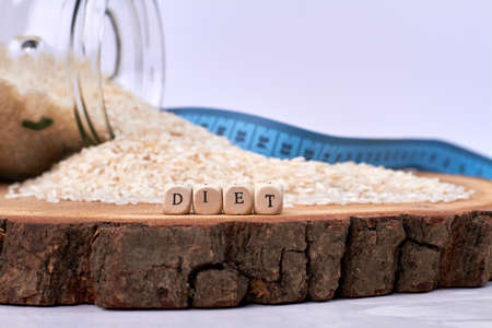Diet and healthy food concept. Heap of white rice on wooden board and measure tape.の写真素材