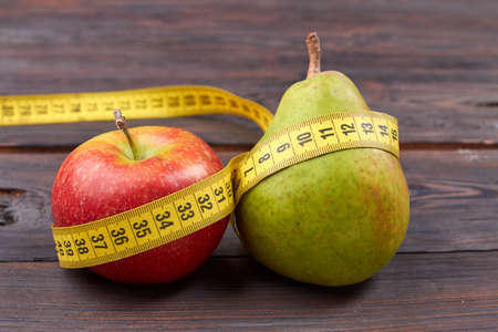 Fresh pear and apple with measure tape. Healthy diet concept. Fruits on wooden table.の写真素材